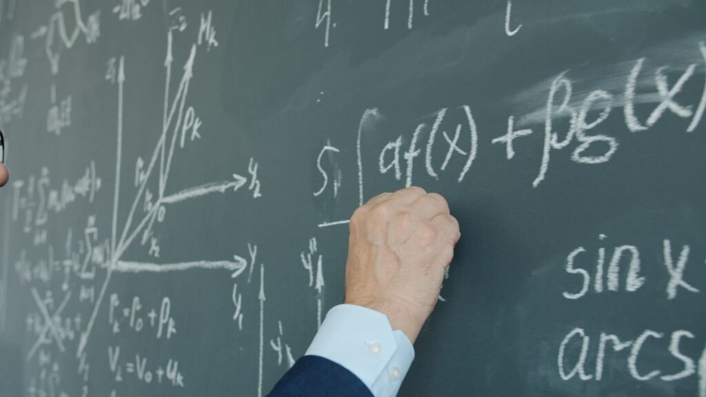 Teacher writing calculus formulas on a blackboard in a Class 11 and 12 Maths class