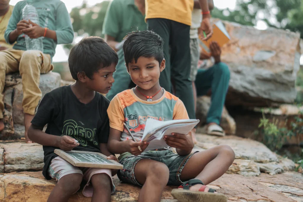 Two young boys reading a book together outdoors