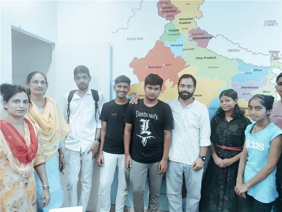 Students and teachers at an Ishkol motivation class, standing in front of a map of India