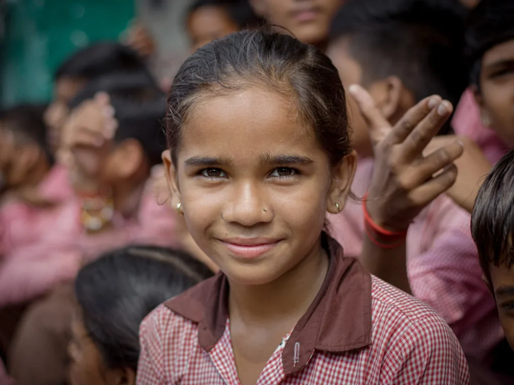 A smiling schoolgirl in uniform with her classmates